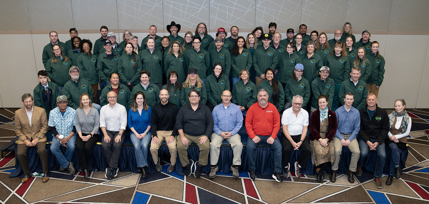 Invasive species ambassadors in matching green jackets pose for a group photo,